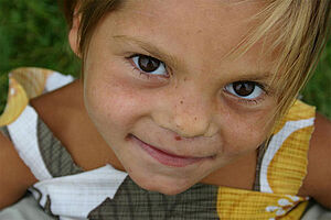 Ein Mädchen im Kindergartenalter lächelt und schaut in die Kamera