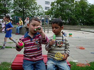 Zwei Jungen im Kindergartenalter essen Wassereis auf dem Spielplatz