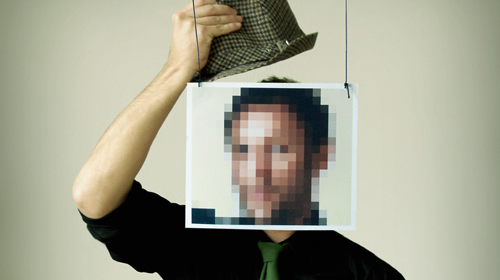Ein junger Mann grüßt in die Kamera und lüftet dabei seinen Hut, sein Gesicht ist von einem Rahmen umgeben und verpixelt