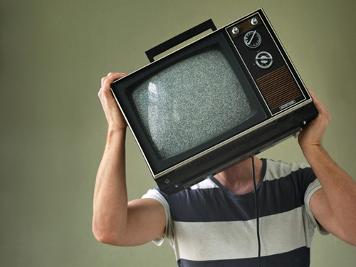 Ein Mann hält sich einen alten Fernseher vor das Gesicht